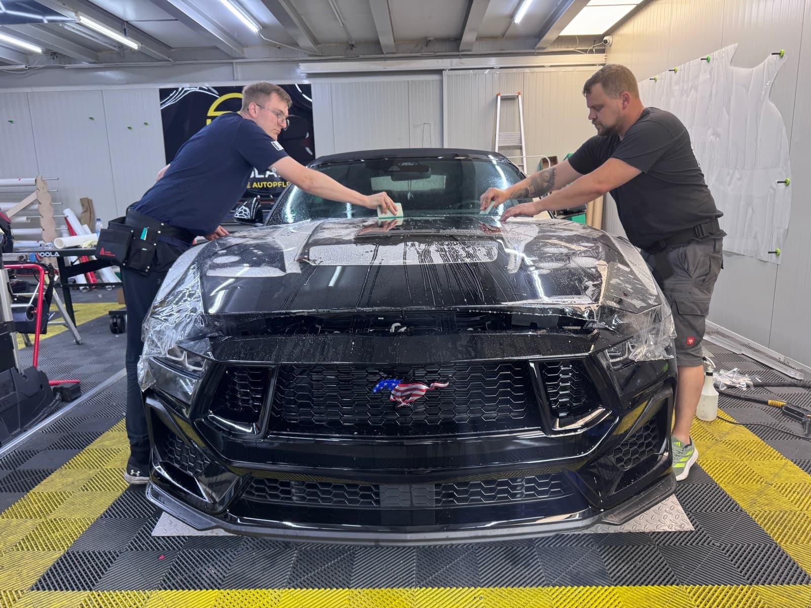 Ford Mustang während der Lackschutzfolierung – zwei Spezialisten