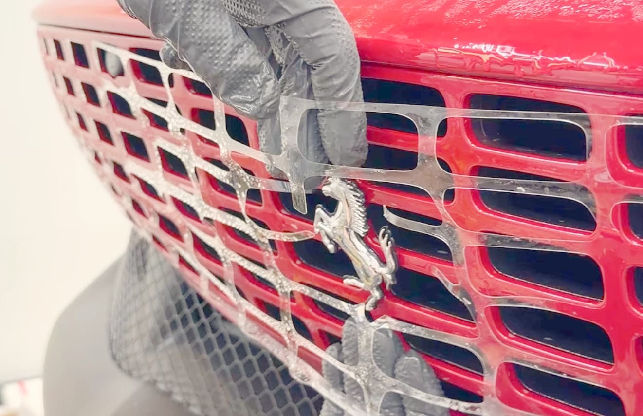 Nasse Anbringung der zugeschnittenen Lackschutzfolie am Kühlergrill eines Ferrari bei Royal Glanz München